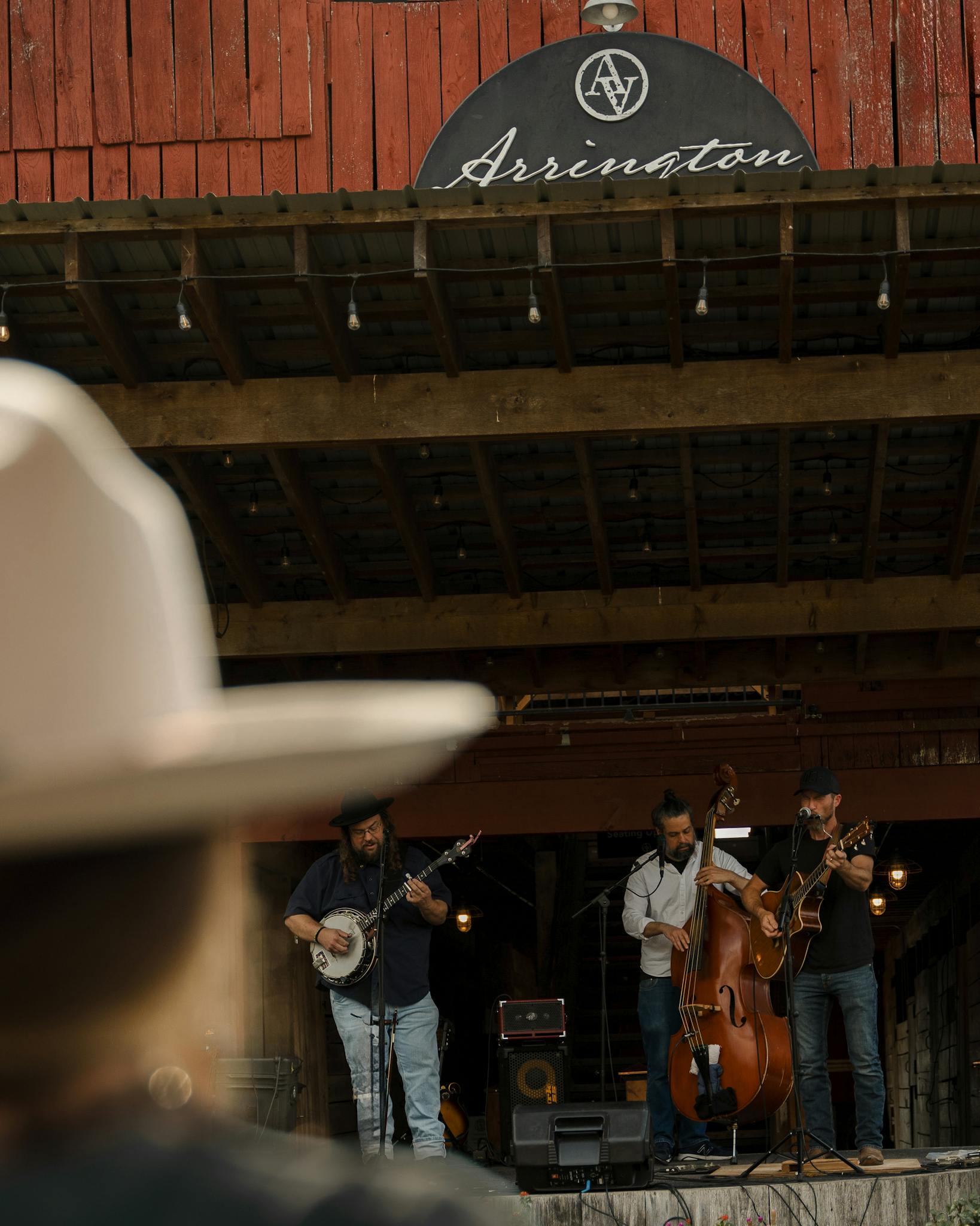 A bluegrass band performing live on a rustic wooden stage at an outdoor venue.