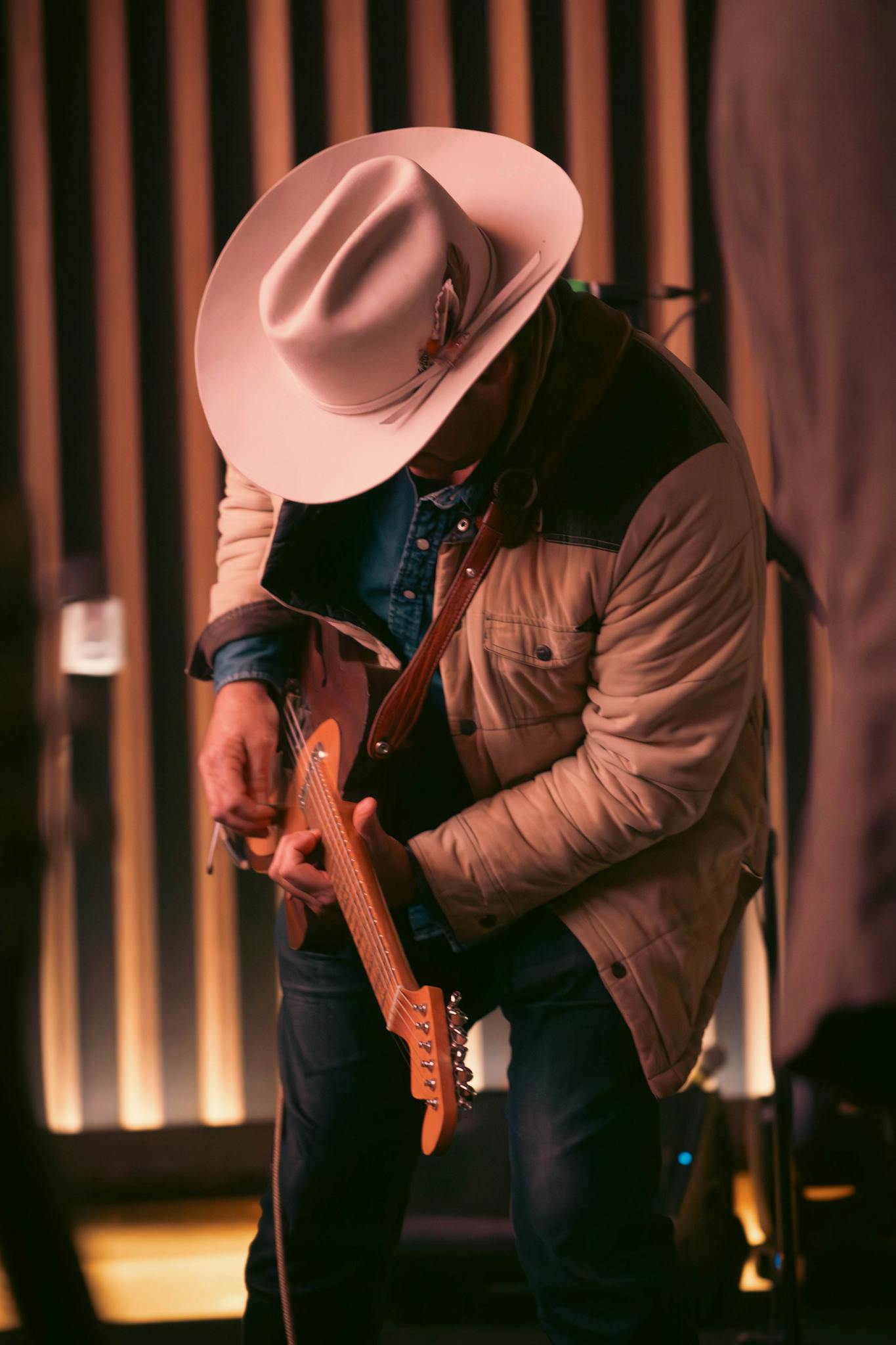 A cowboy musician passionately playing an electric guitar on stage, bringing western style to music.