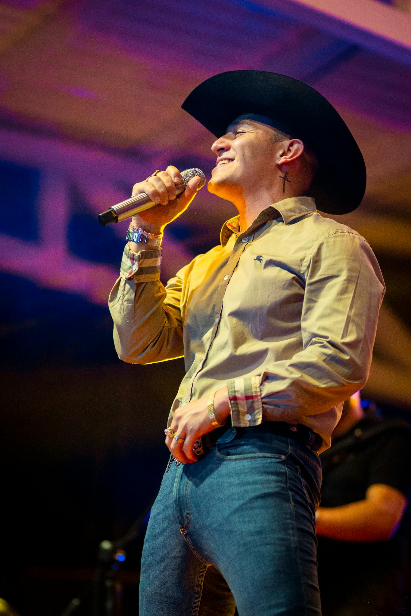 A male performer in a cowboy hat sings passionately on stage, creating an engaging performance atmosphere.